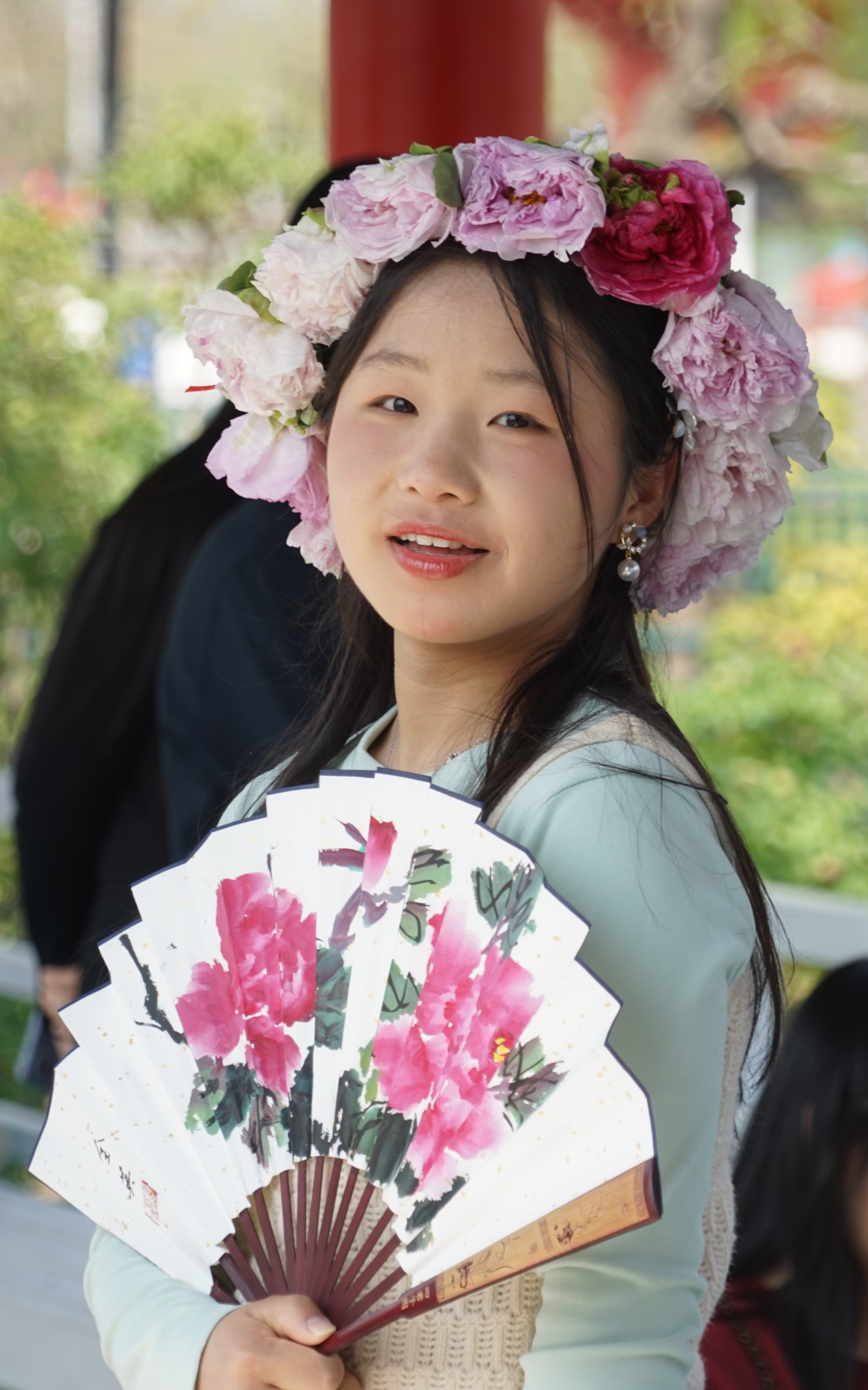 A girl wearing a peony wreath and holding a peony-adorned fan is seen during the 33rd Heze International Peony Cultural Tourism Festival in Heze, Shandong Province on April 8, 2024. /IC