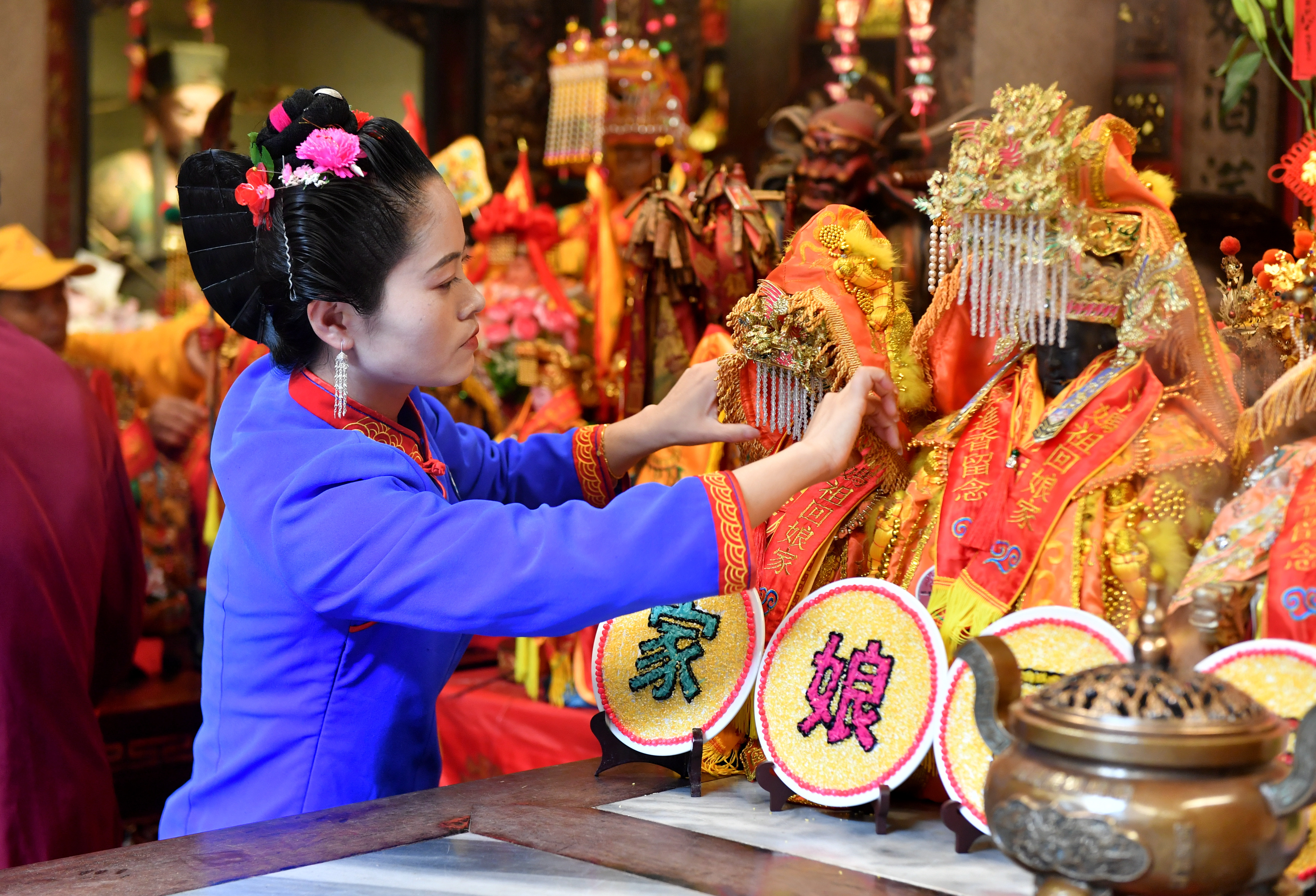 A woman takes care of the Mazu statues brought by devotees from across the world at Mazu Temple on Meizhou Island in Fujian Province on April 9, 2024. /IC