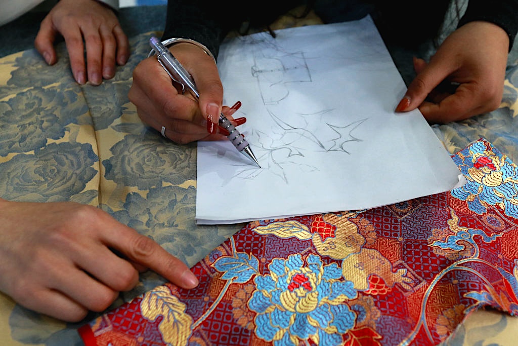A designer draws peony patterns on a blueprint of a horse-face skirt in Caoxian County, Shandong Province on March 4, 2024. /CFP