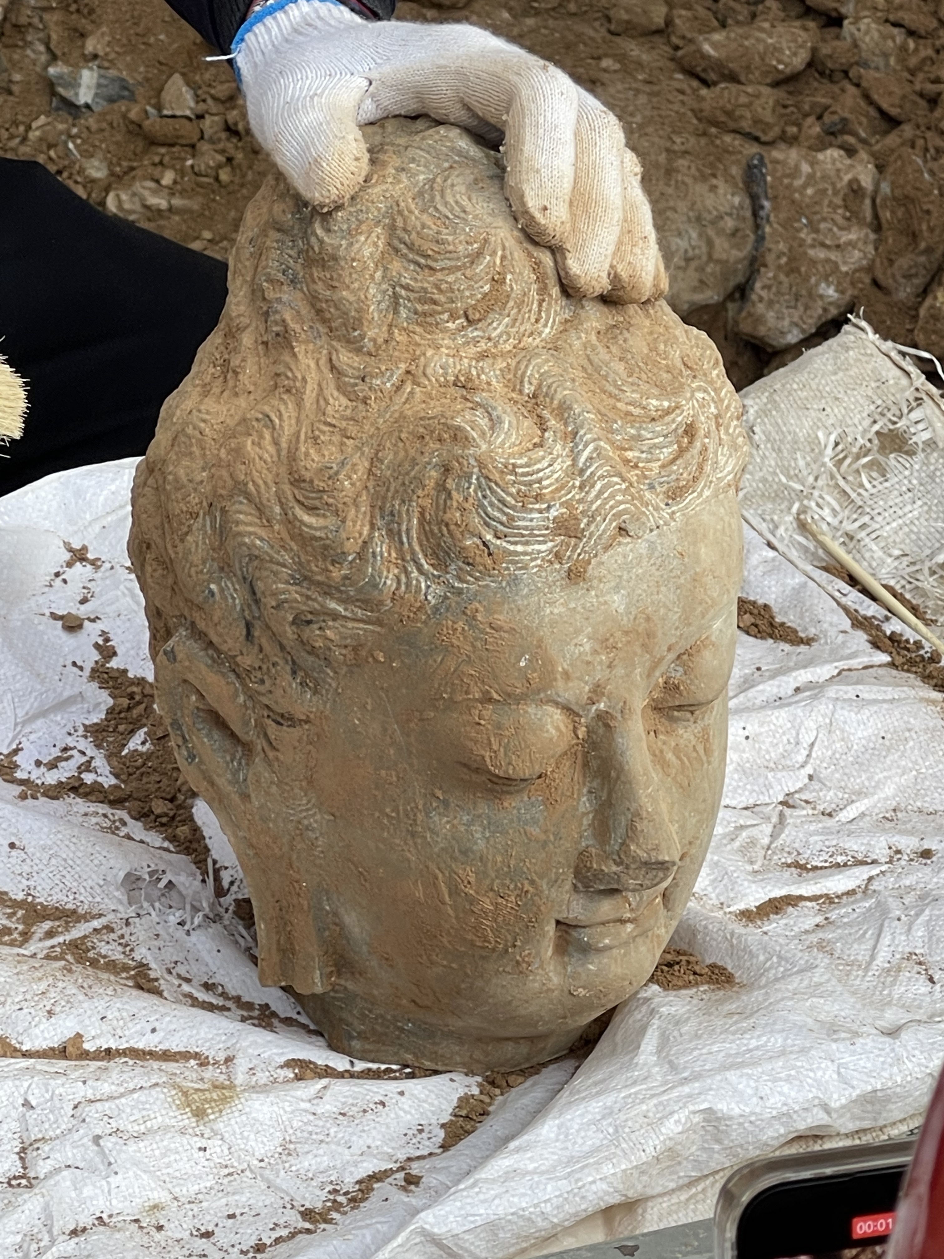 The head from a carving of the Buddha dating back to the Tang Dynasty has been discovered in the Leigutai South Cave at Luoyang's Longmen Grottoes. /CGTN