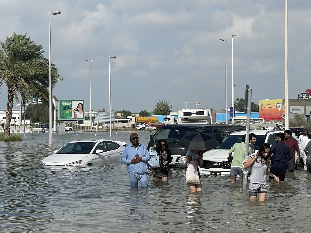 People wade through submerged streets in a flooded area as heavy rain negatively affects daily life in Dubai, United Arab Emirates, April 17, 2024. /CFP