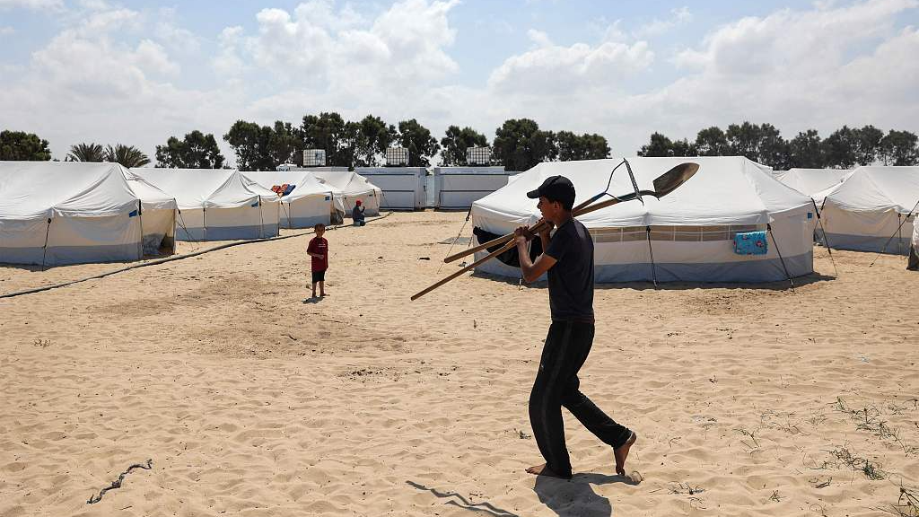 A young Palestinian man carries tools at a camp for displaced Palestinians in Rafah, Gaza, April 14, 2024. /CFP
