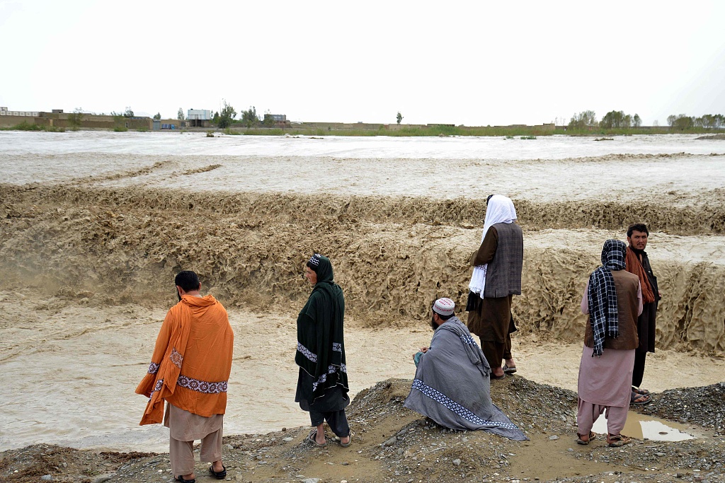 Afghan people wait to cross a flooded area in Spin Boldak district of Kandahar province after a flash flood following a heavy rainfall, April 13, 2024. /CFP