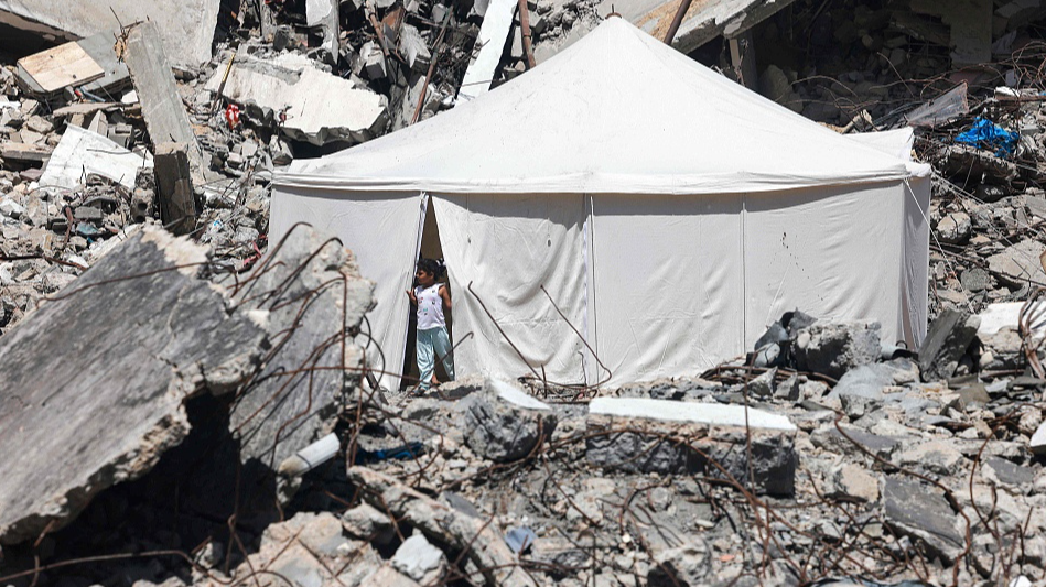 A displaced Palestinian stands at the entrance of a tent amid the rubble of a building damaged during Israel's bombardment in Rafah, southern Gaza, April 19, 2924. /CFP