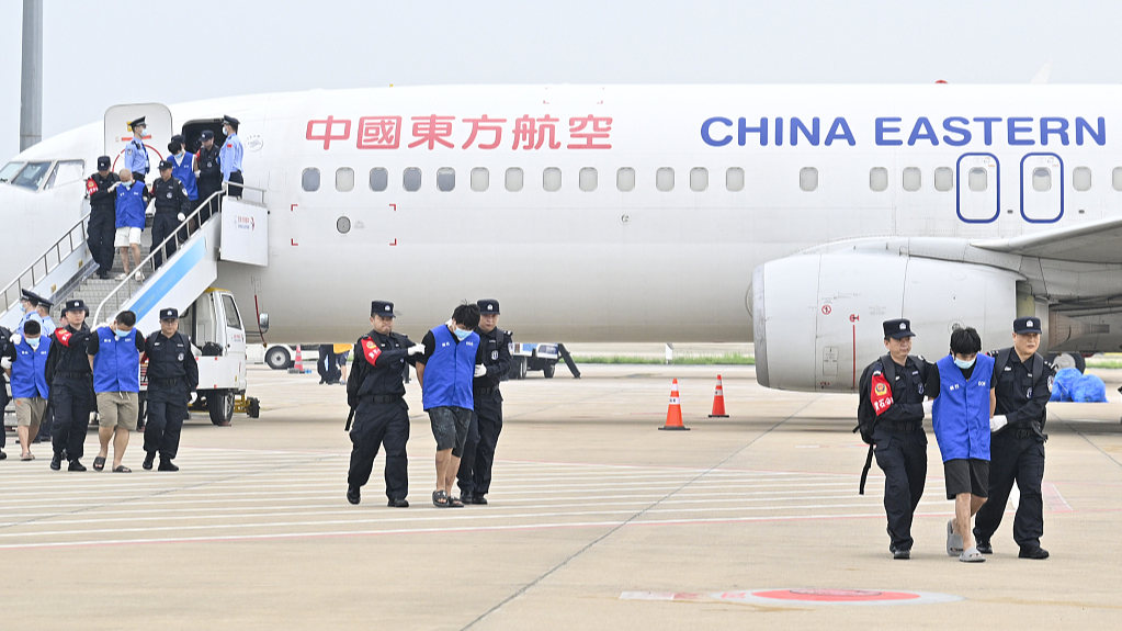 Gambling and scam suspects are escorted by Chinese police officers at Wuhan Tianhe International Airport in Wuhan, central China's Hubei Province, April 13, 2024. /CFP