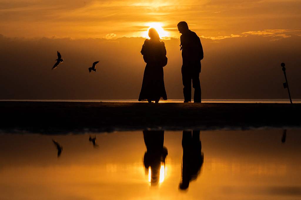 People enjoy the sunset on the beach of Deauville, France. /CFP