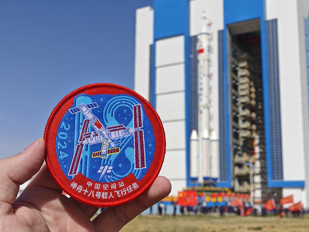 An official badge for the Shenzhou-18 manned space mission is seen in front of a rocket at the Jiuquan Satellite Launch Center, northwest China, April 17, 2024. /CFP