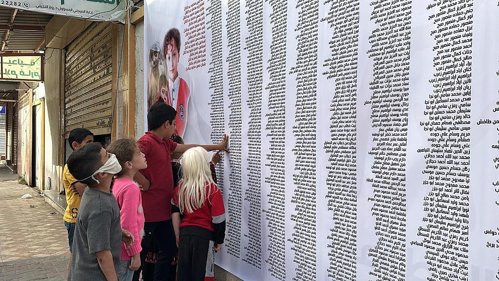 Palestinian children look at a banner displaying the names of deceased children during a memorial ceremony in the courtyard of Kuwait Hospital held in memory of thousands of Palestinian children killed by Israel in Rafah, Gaza, April 23, 2024. /CFP