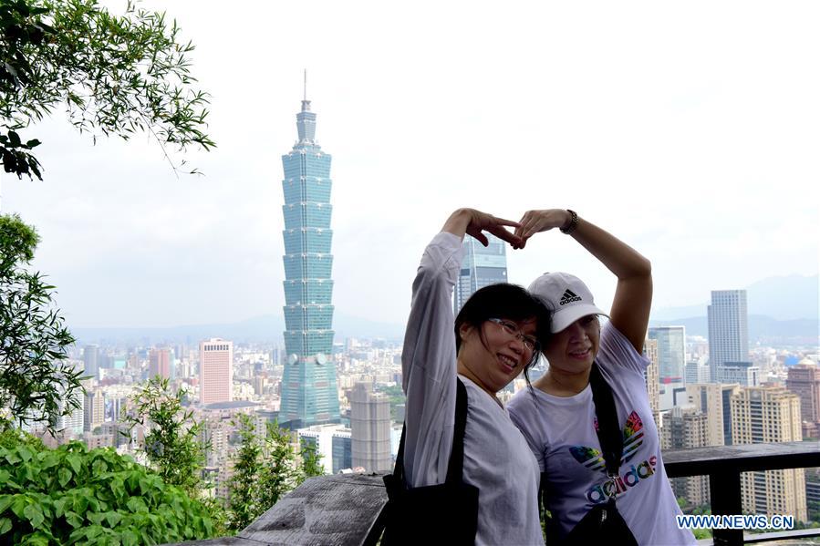 Tourists pose for a photo on Xiangshan Mountain in Taipei, southeast China's Taiwan, July 21, 2019. /Xinhua