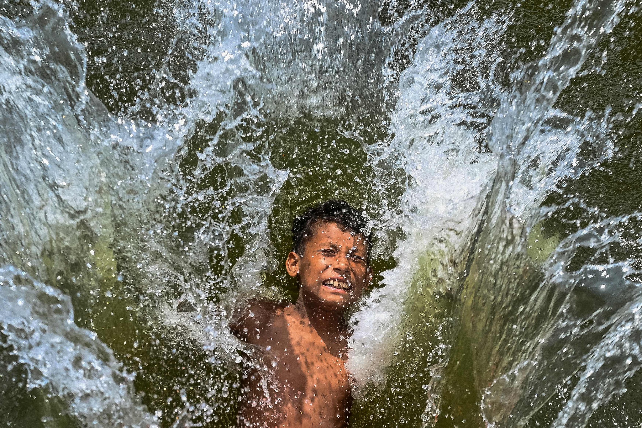 A child playfully takes a dip in a lake to get respite from the heat on a summer afternoon in Dhaka, Bangladesh, April 29, 2024. /CFP