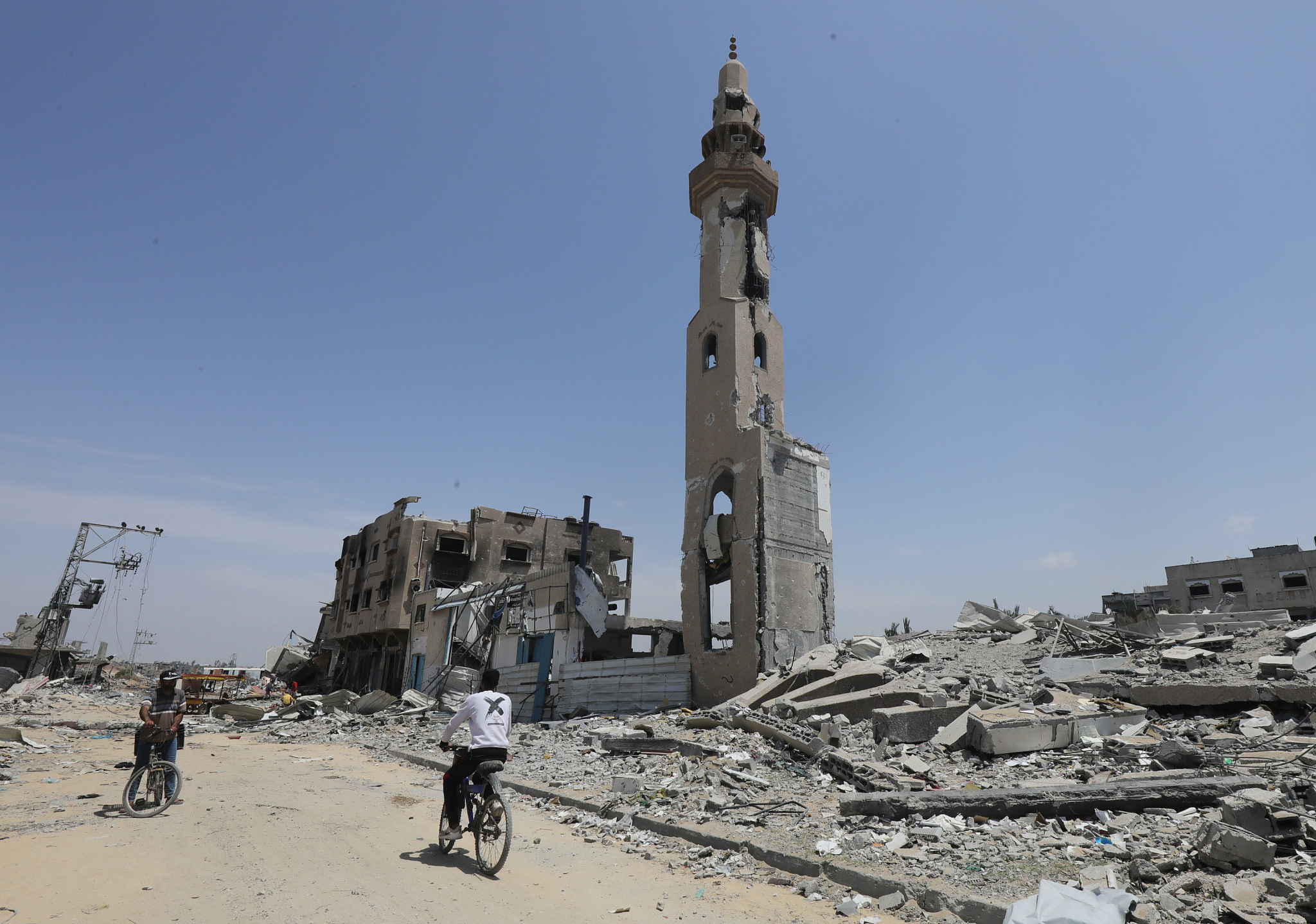 Palestinians walk between destroyed buildings in the north of Nusairat refugee camp, southern Gaza Strip, April 30, 2024. /CFP