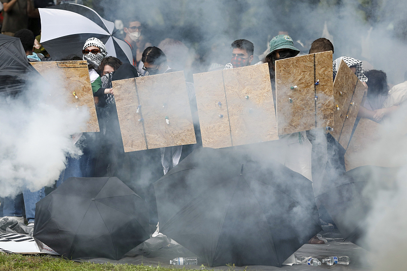Pro-Palestinian protesters form a barricade as law enforcement shoots tear gas in their direction at the University of South Florida MLK Plaza Fountain in Tampa, Florida, April 30, 2024. /CFP