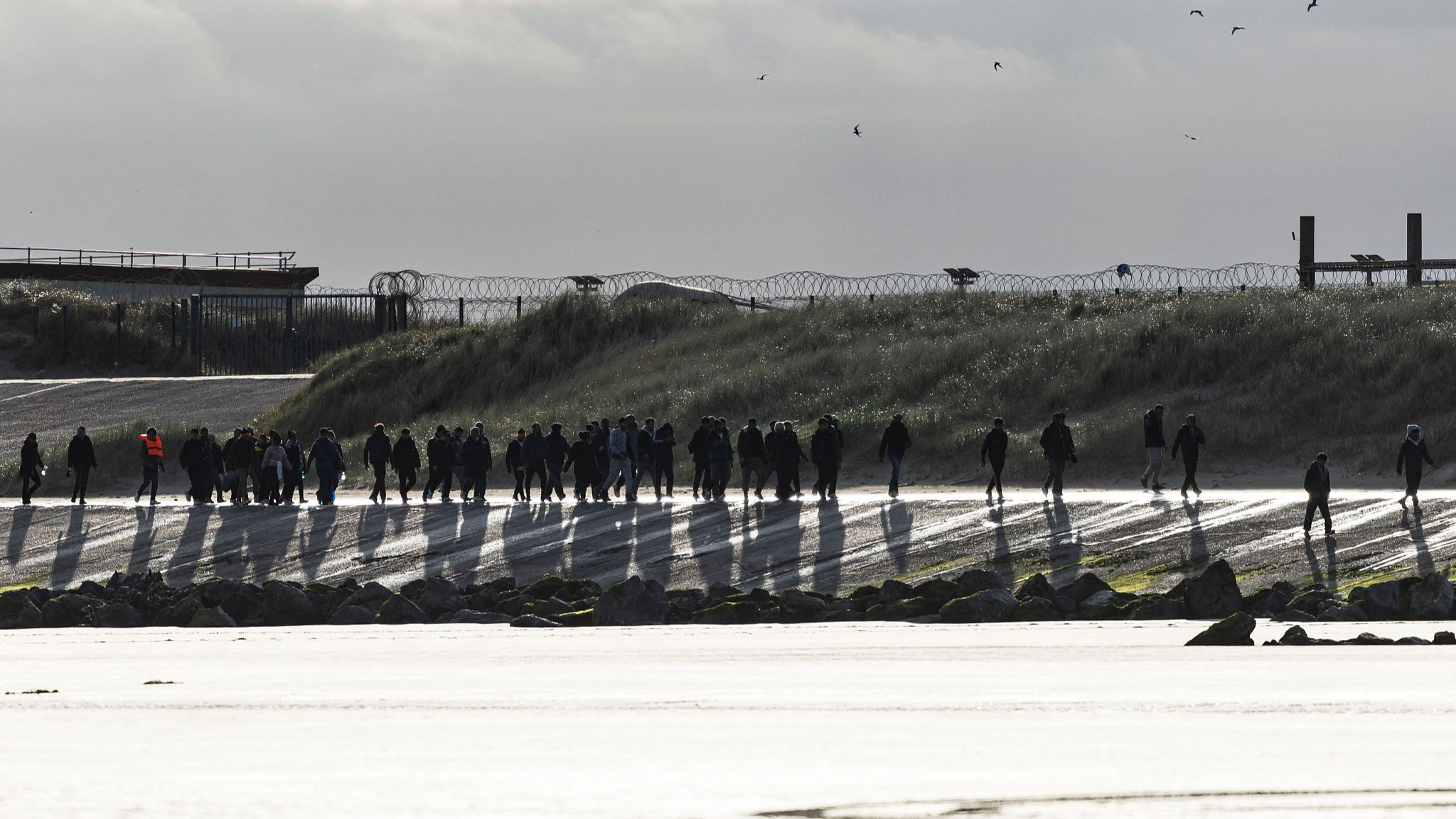 Migrants cross the beach to try to board a smuggler's boat in an attempt to cross the English Channel, on the beach of Gravelines, near Dunkirk, northern France, April 26, 2024. /CFP