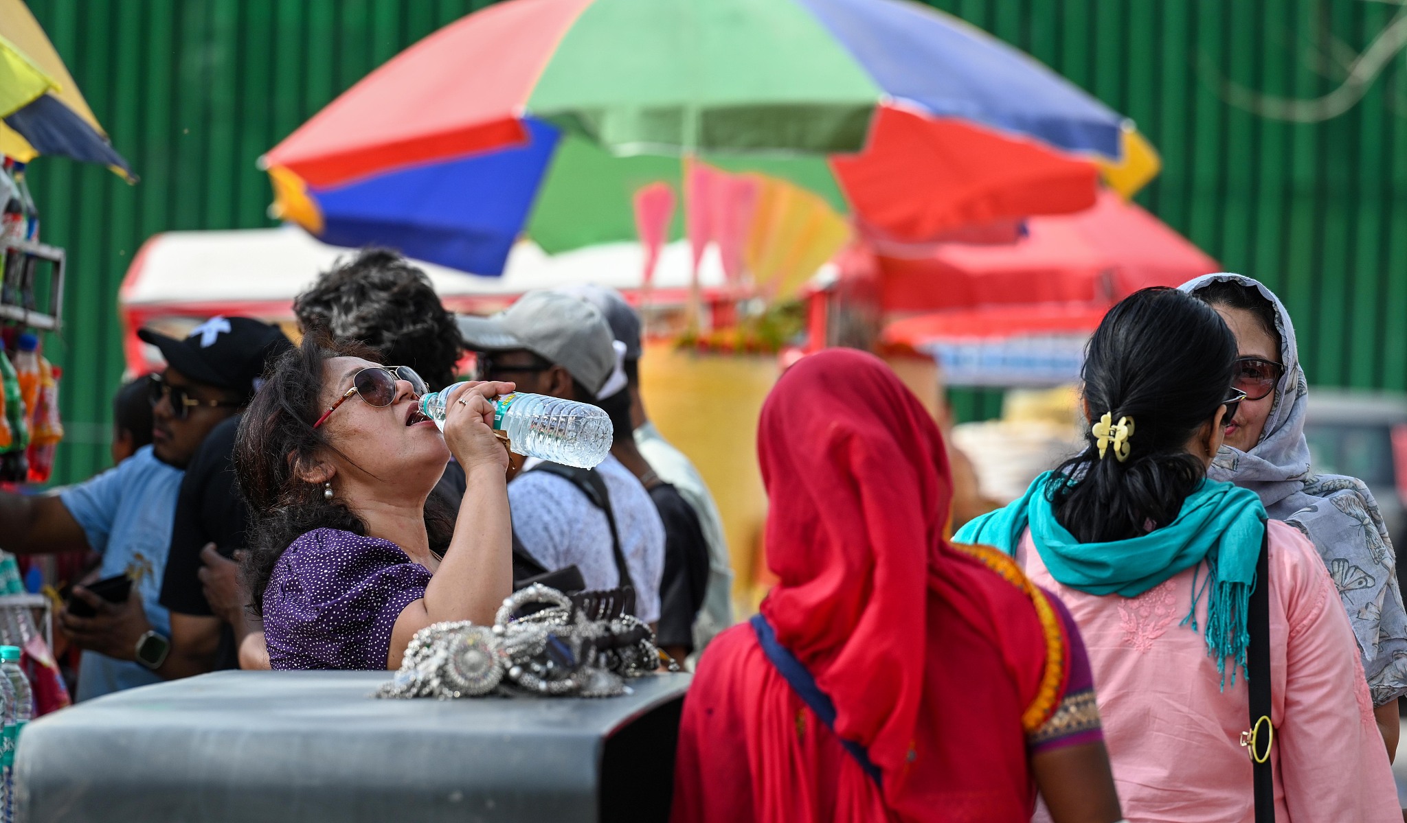 A visitor drinking water from a bottle during a hot summer day, near India Gate in New Delhi, India on April 20, 2024. /CFP