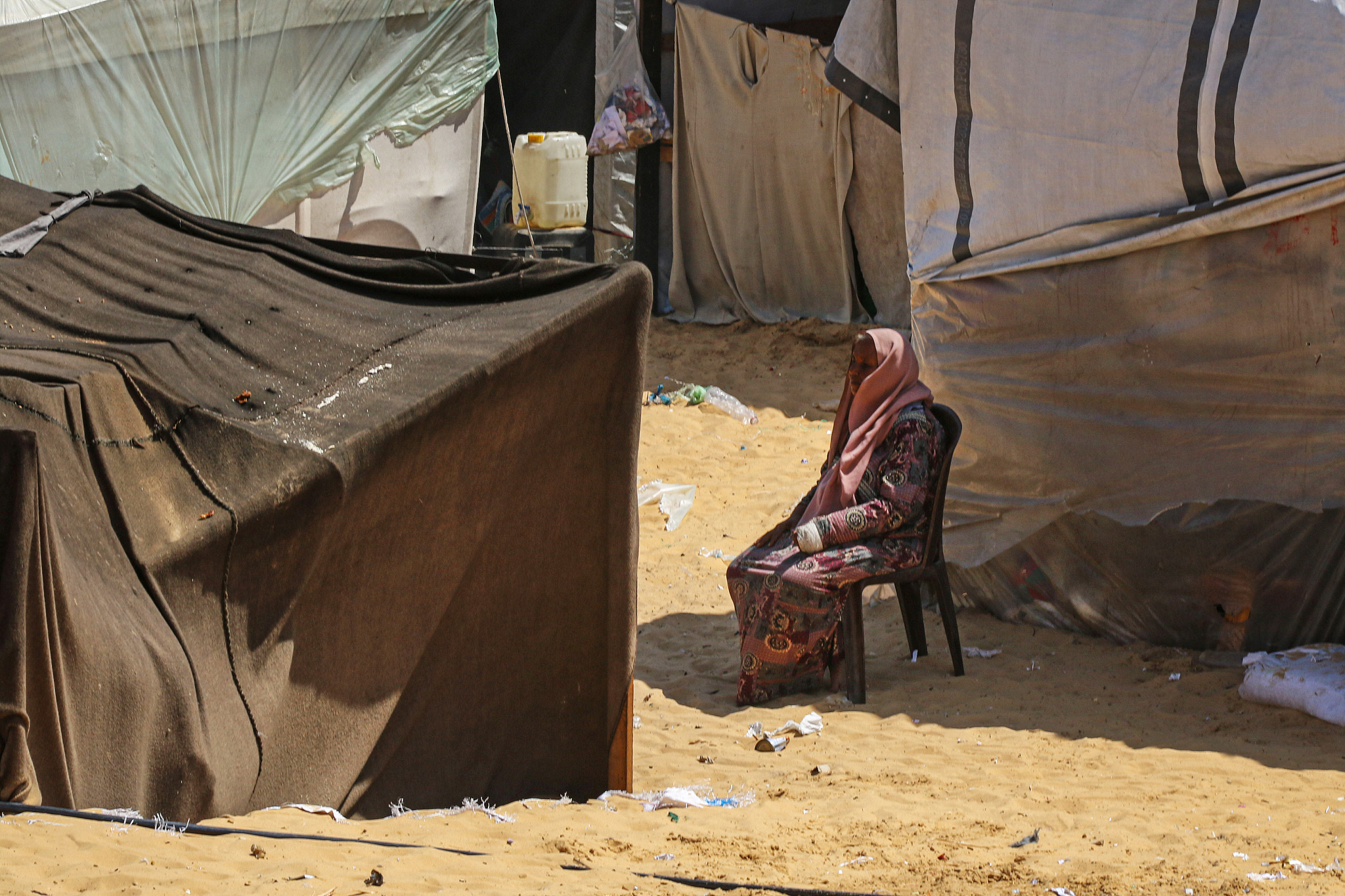 A displaced Palestinian woman shelters from the sun beside a makeshift tent at a camp in Rafah, southern Gaza, May 3, 2024. /CFP