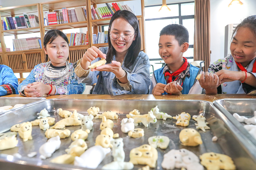 A teacher shows students how to make dog-shaped snacks at a primary school in Hangzhou, Zhejiang Province, April 29, 2024. Making dog-shaped snacks is a tradition of the Yuhang District of Hangzhou, carrying the wish from the parents that their children will be as healthy and vivacious as puppies. /CFP