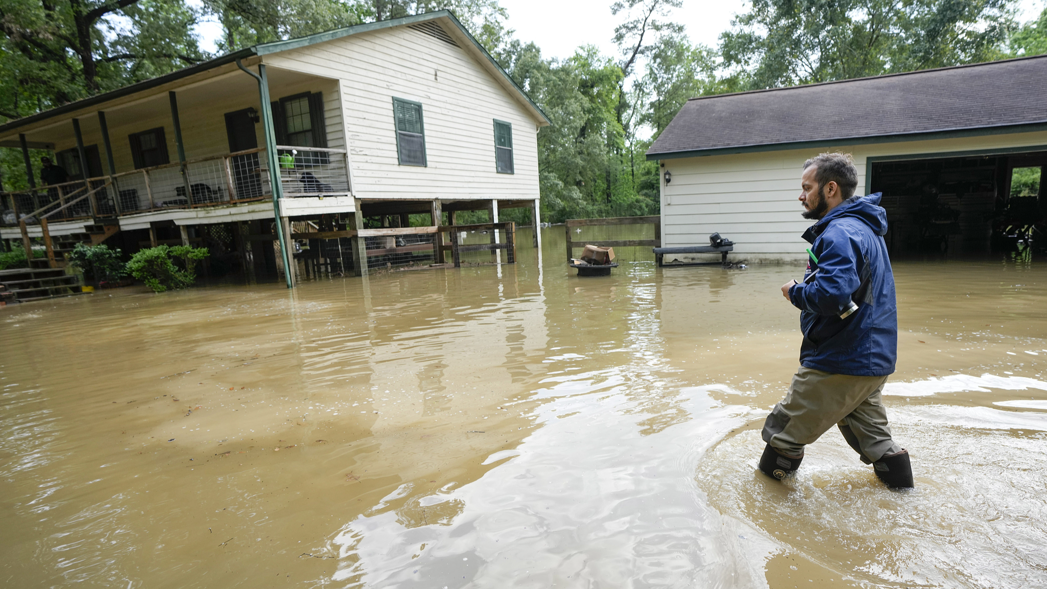 A man wades through floodwaters from Peach Creek to get to his house, New Caney, Texas, May 3, 2024. /CFP