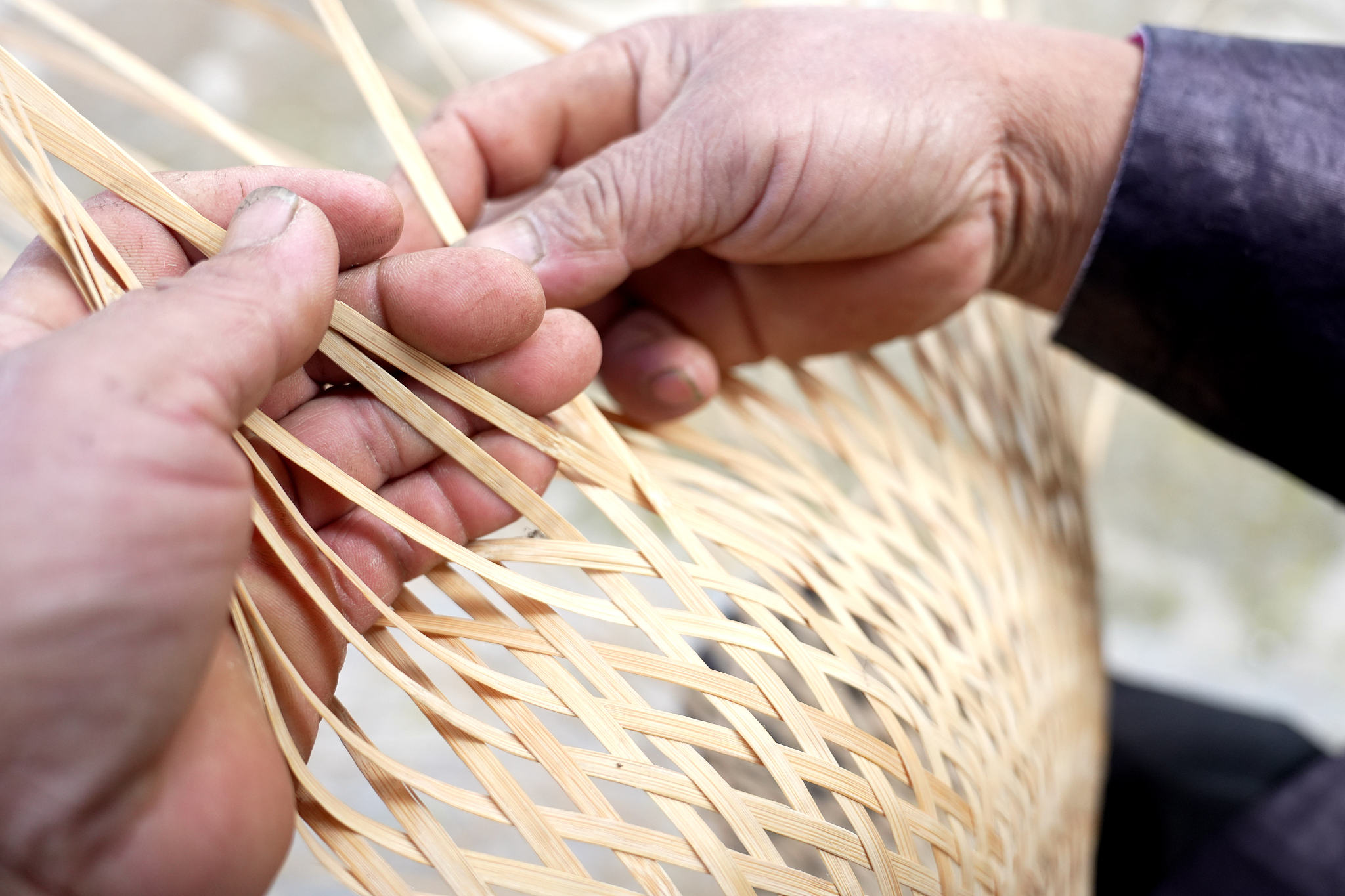 A person weaving bamboo into household utensils. /CFP