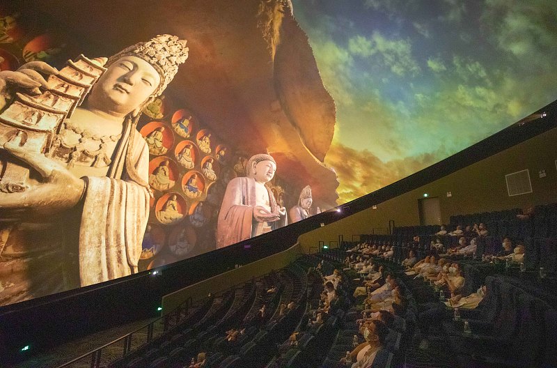 Visitors watch a film about the Dazu Rock Carvings in an immersive experience space at the Dazu Rock Carvings scenic spot, Chongqing Municipality. /CFP