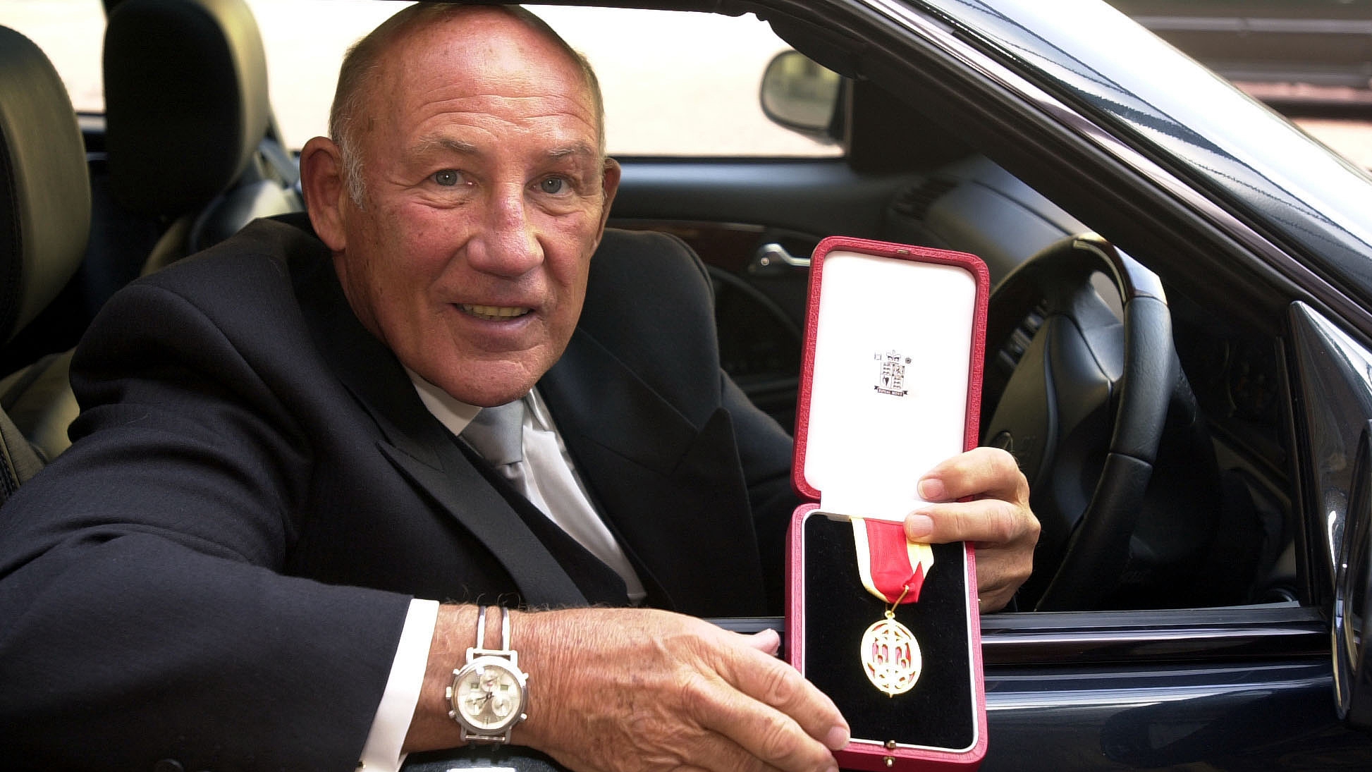 Sir Stirling Moss displays his knighthood from the Prince of Wales at Buckingham Palace in London, England, March 21, 2000. /CFP