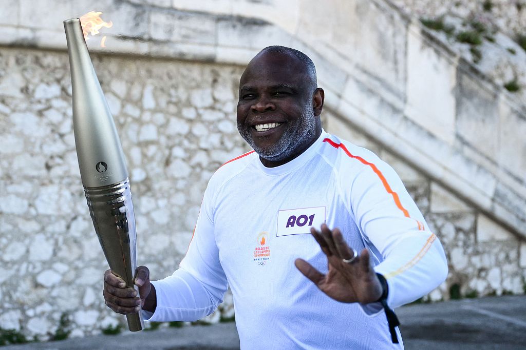 Basile Boli, a former star football player for France, carries the Olympic torch at the Notre Dame de la Garde Basilica in Marseille, France, May 9, 2024. /CFP