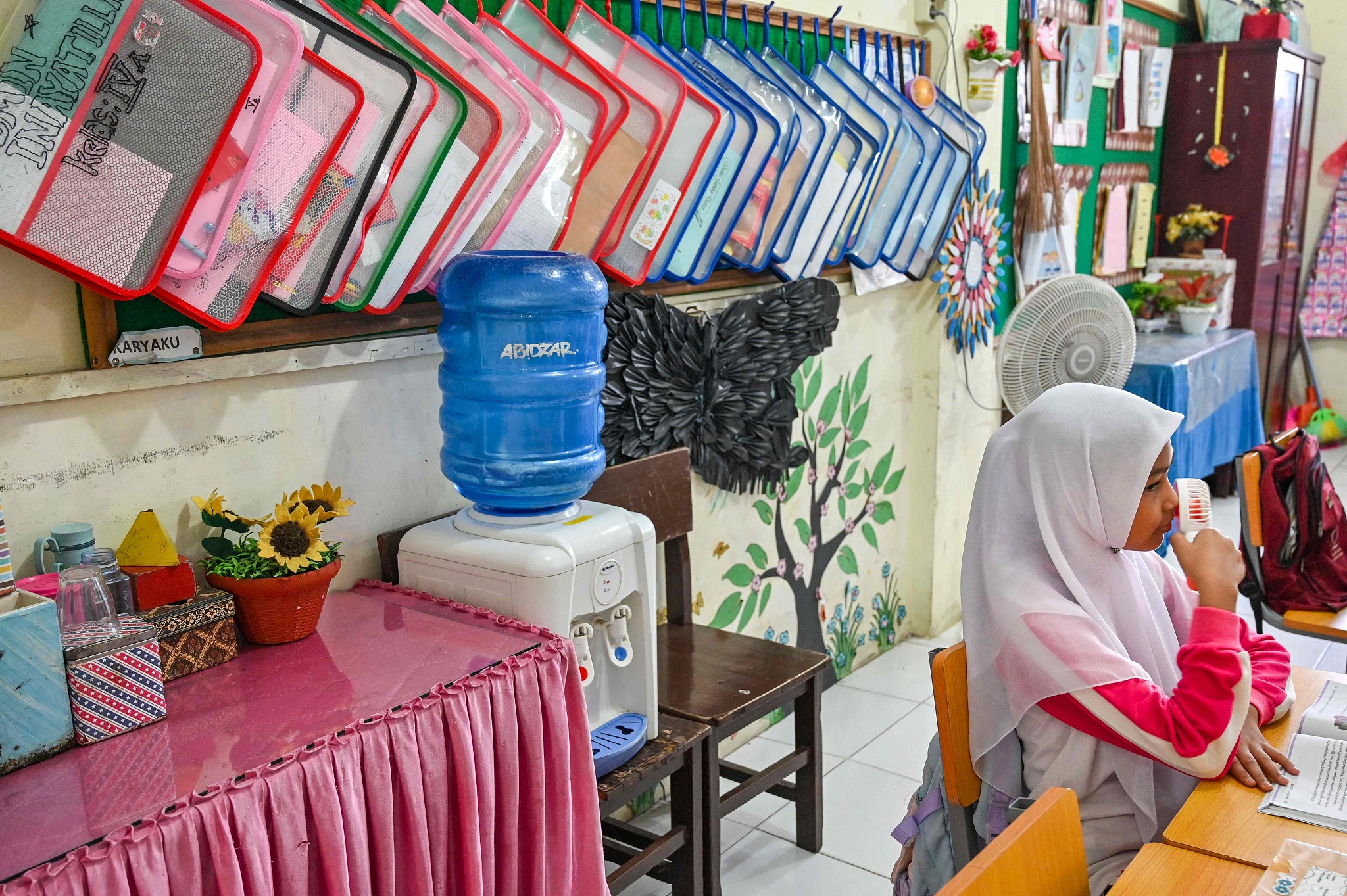 A student uses a portable fan to keep cool in the classroom during a heat wave at a primary school in Banda Aceh on May 7, 2024. /CFP