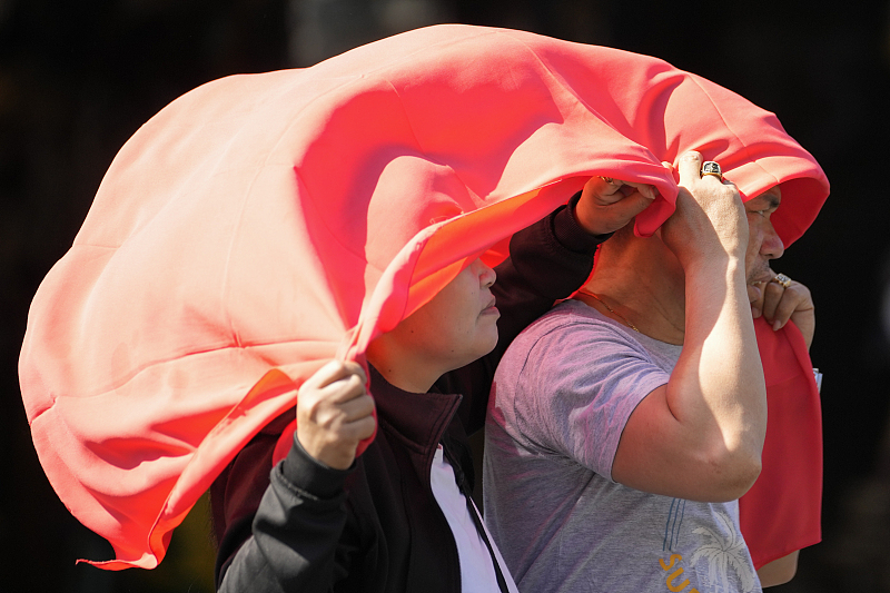 A man and a woman use a cloth to protect them from the sun in Manila, the Philippines, April 29, 2024. /CFP 
