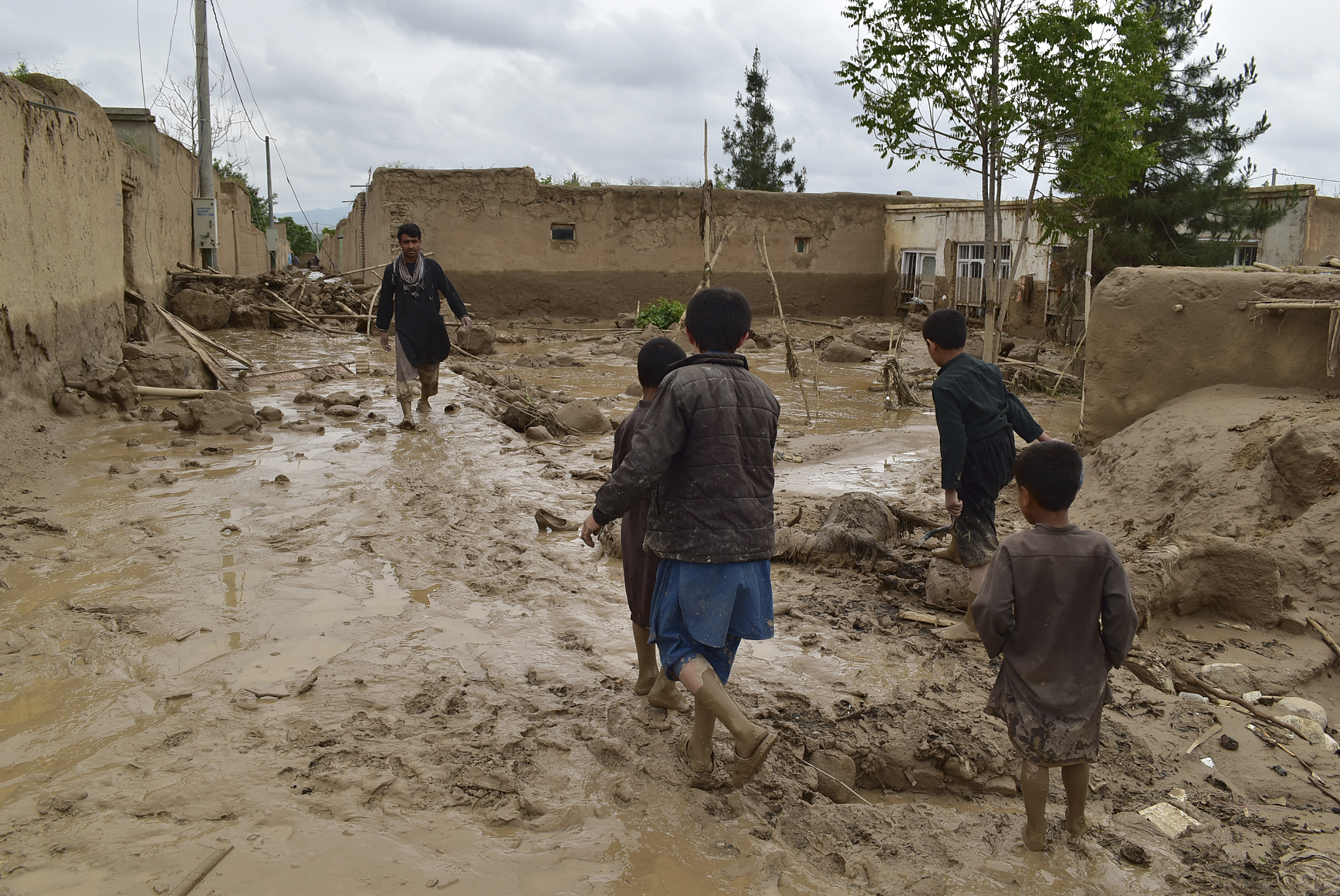People walk near their damaged homes after heavy flooding in Baghlan province in northern Afghanistan, May 11, 2024. /CFP