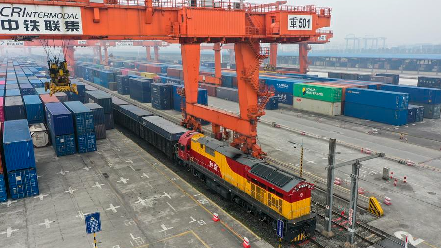 This aerial photo shows a rail-sea intermodal freight train carrying containers of goods, including cars, motorcycles, engines, and sodium carbonate, at Tuanjie Village Central Station in southwest China's Chongqing Municipality, January 22, 2023. /Xinhua