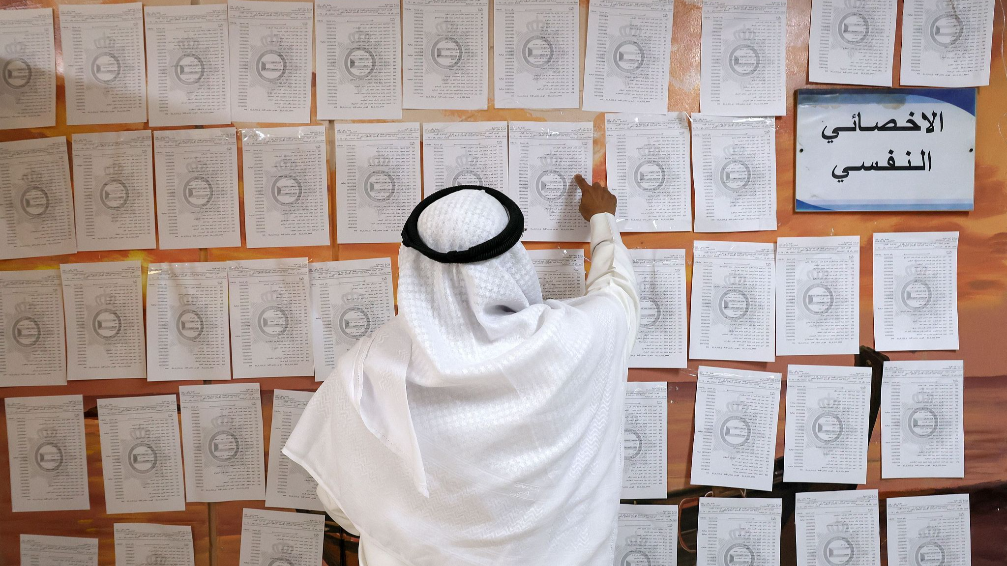 A Kuwaiti man consults electoral lists before casting his vote in parliamentary elections at a polling station in Kuwait City, Kuwait, April 4, 2024. /CFP