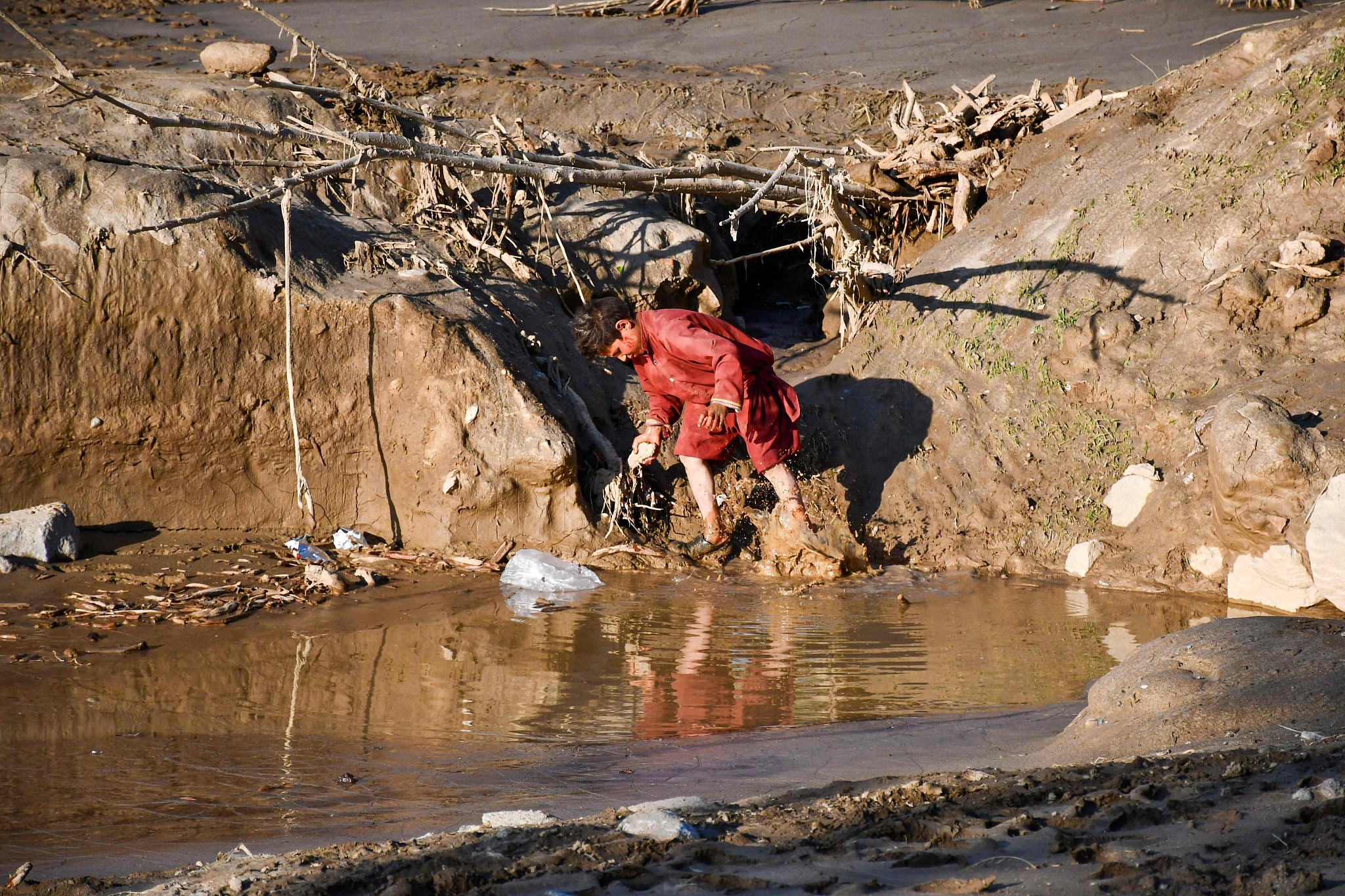 A boy walks in muddy waters after floods in Burka district of Baghlan province  in Afghanistan, May 12, 2024. /CFP