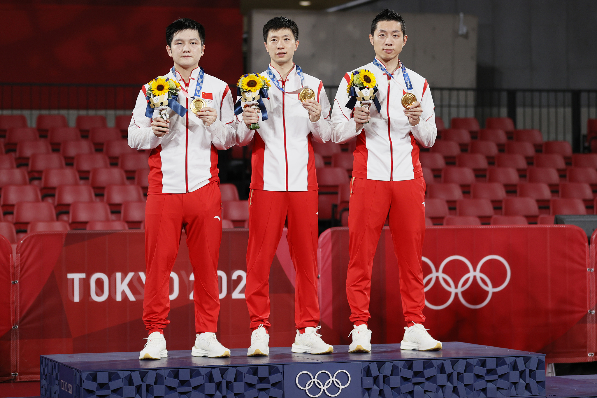 L-R: Fan Zhendong, Ma Long, and Xu Xin celebrate on the podium after winning the gold medal in the table tennis men's team final during the Tokyo 2020 Olympic Games in Tokyo, Japan, August 6, 2021. /CFP
