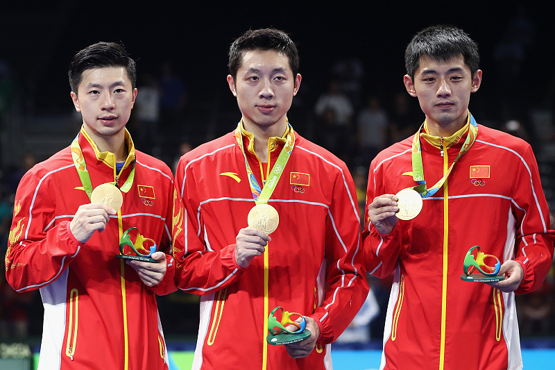 L-R: Ma Long, Xu Xin, and Zhang Jike celebrate on the podium after winning the gold medal in the table tennis men's team final during the Rio 2016 Olympic Games in Rio de Janeiro, Brazil, August 17, 2016. /CFP