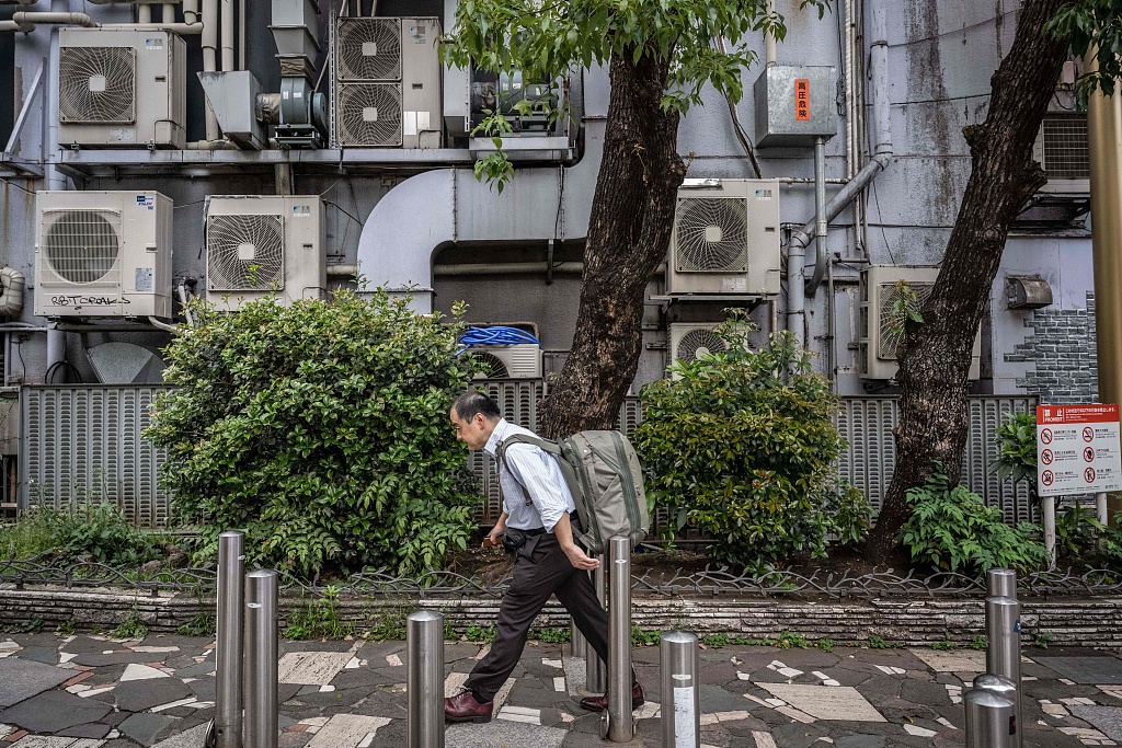 A man walking past air conditioning units on a building in Tokyo, Japan, April 30, 2024. /CFP