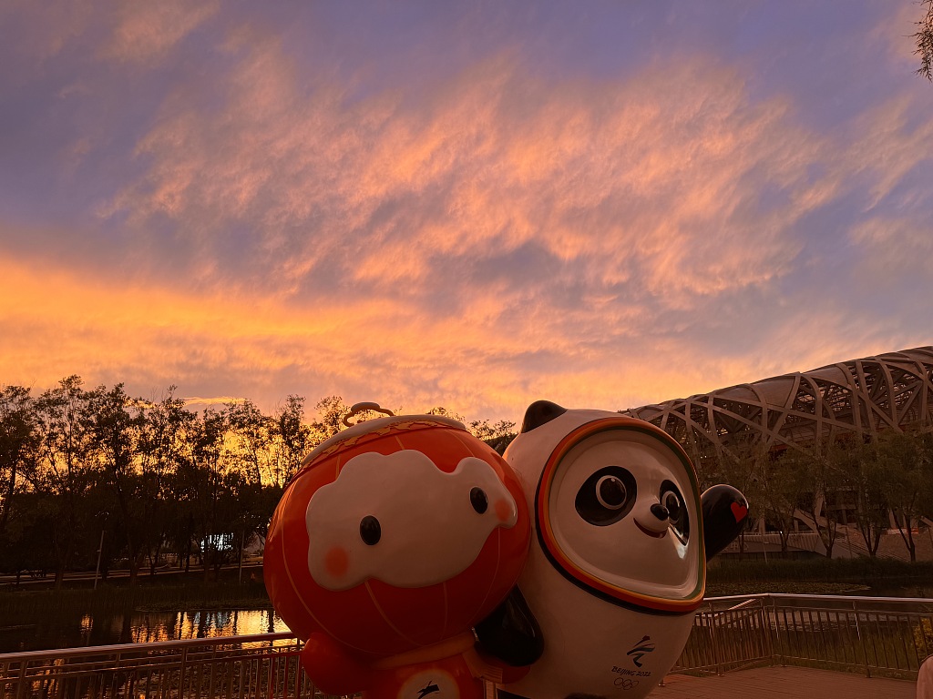 The sun sets behind mascots Shuey Rhon Rhon and Bing Dwen Dwen at the Bird's Nest Stadium in Beijing, May 14, 2024. /CFP