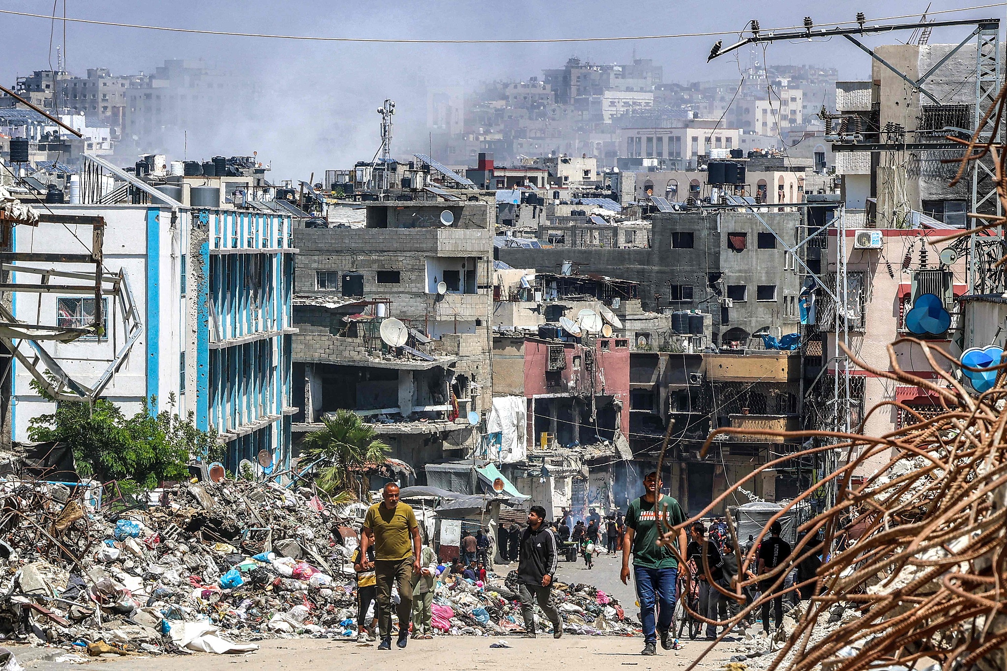 People walk past a mound of trash and destroyed buildings during Israeli bombardment in Jabalia in the northern Gaza Strip, May 14, 2024. /CFP