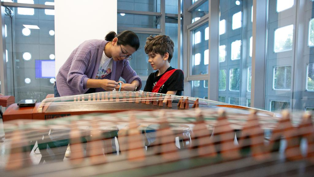 A teacher helps her student to wear fake nails before a guzheng (Chinese zither) class at the China Cultural Center in Belgrade, Serbia, April 29, 2024. /Xinhua