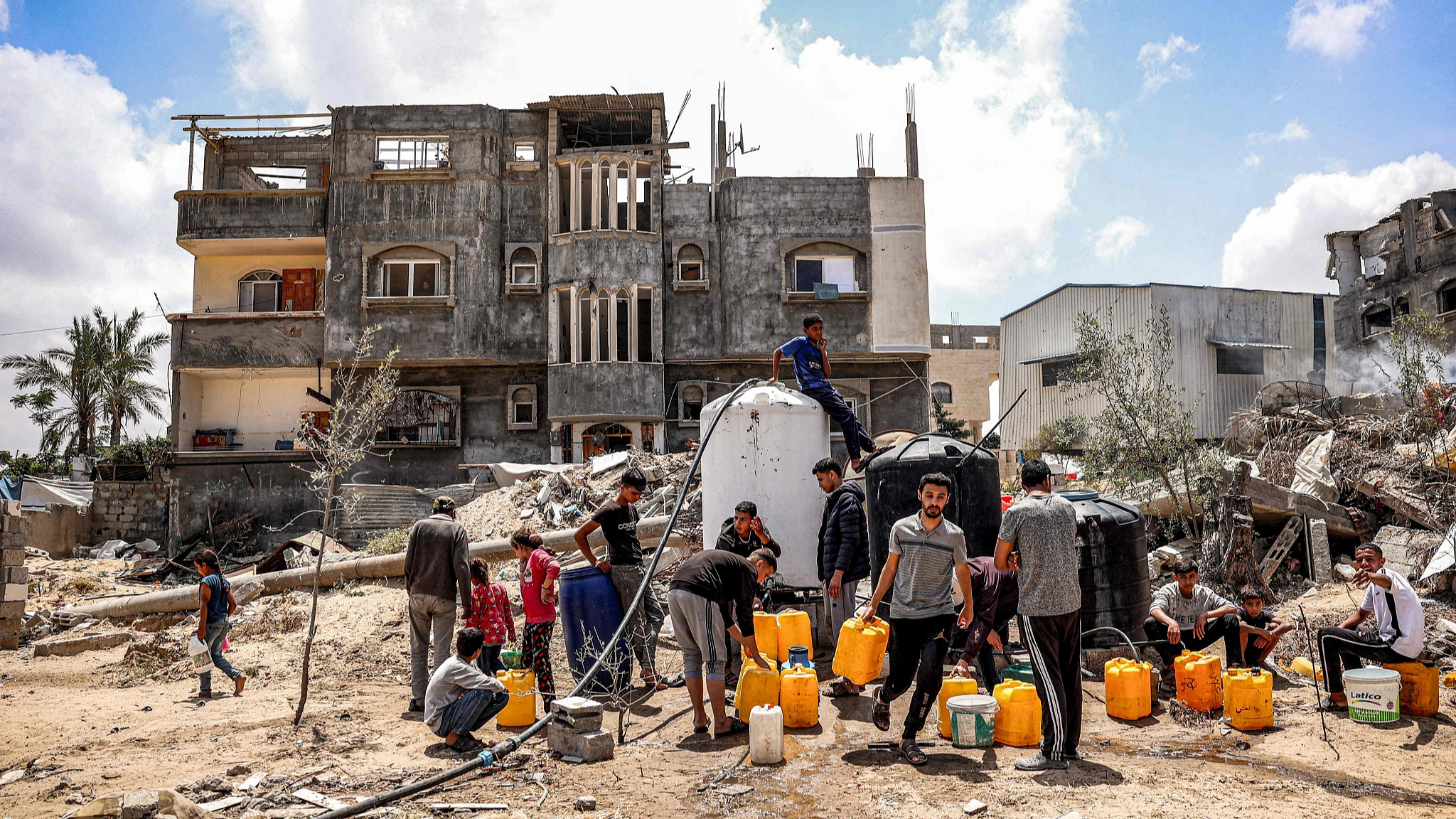 Men and children gather to fill up their jerrycans with water from cisterns in Khan Yunis, southern Gaza, May 14, 2024. /CFP