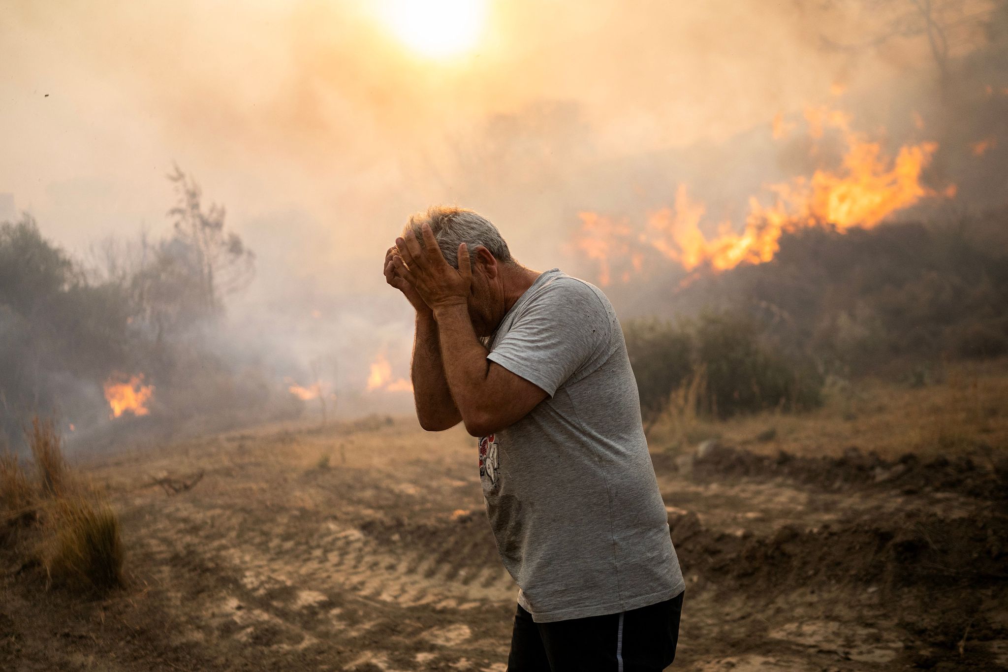 A man reacts as a fire burns into the village of Gennadi on the Greek Aegean island of Rhodes, July 25, 2023. /CFP
