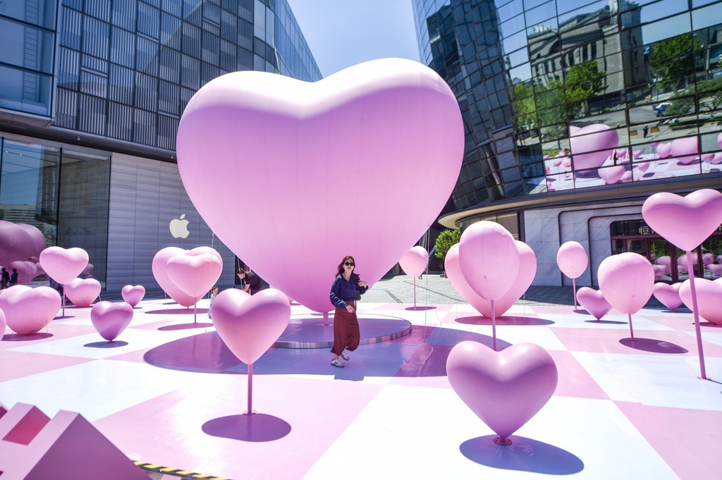 A woman passes by heart-shaped balloons set up in a square outside a mall in Jinan, Shandong Province, May 15, 2024. /IC