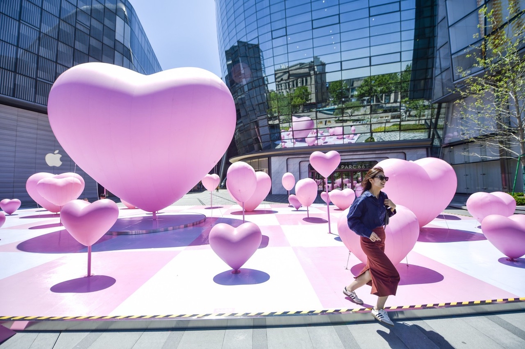 A woman walks past heart-shaped balloons set up in a square outside a mall in Jinan, Shandong Province, May 15, 2024. /IC