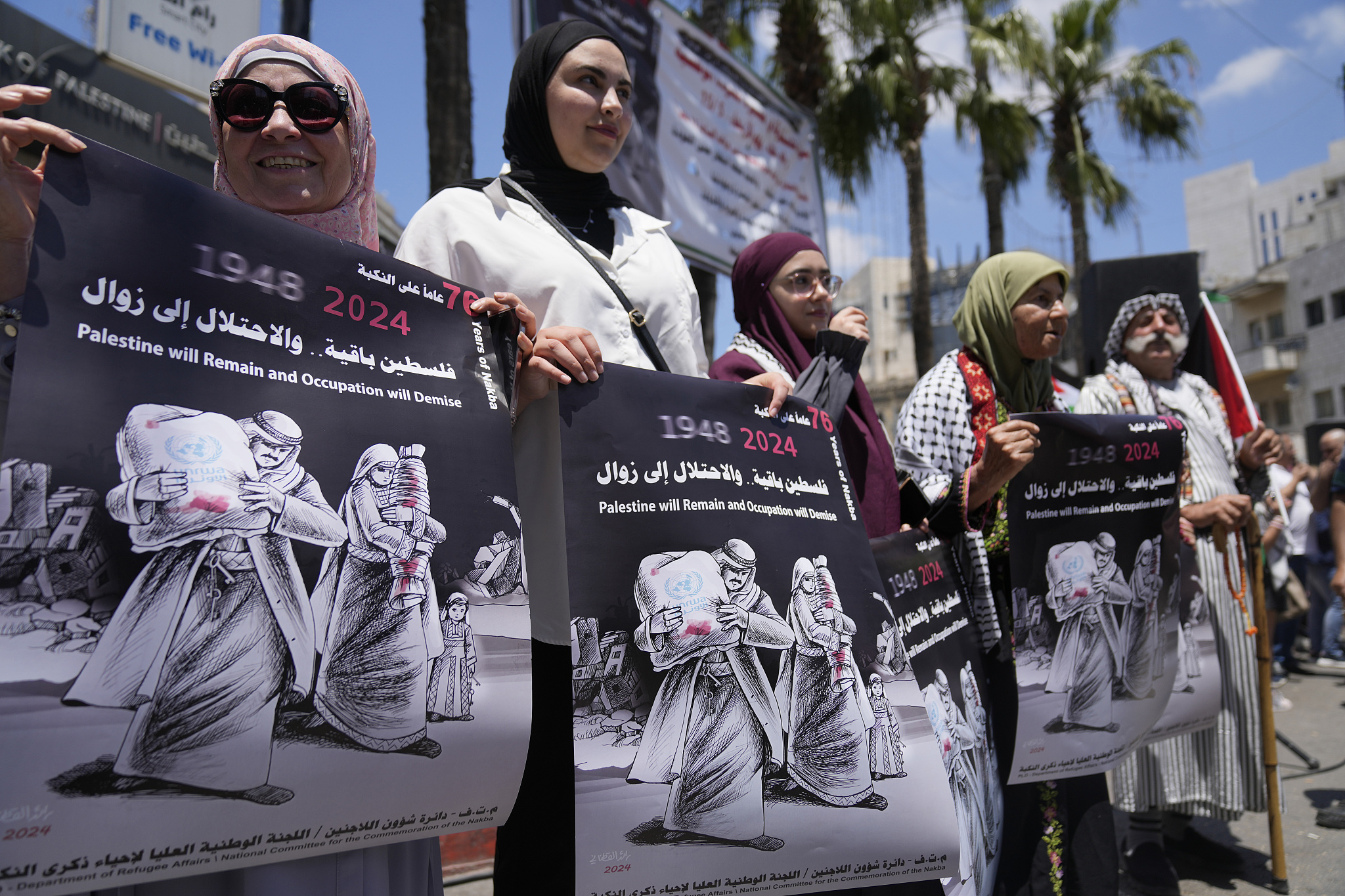 Palestinian women hold posters during a mass ceremony to commemorate the Nakba Day, Arabic for catastrophe, in the West Bank city of Ramallah, May 15, 2024. /CFP