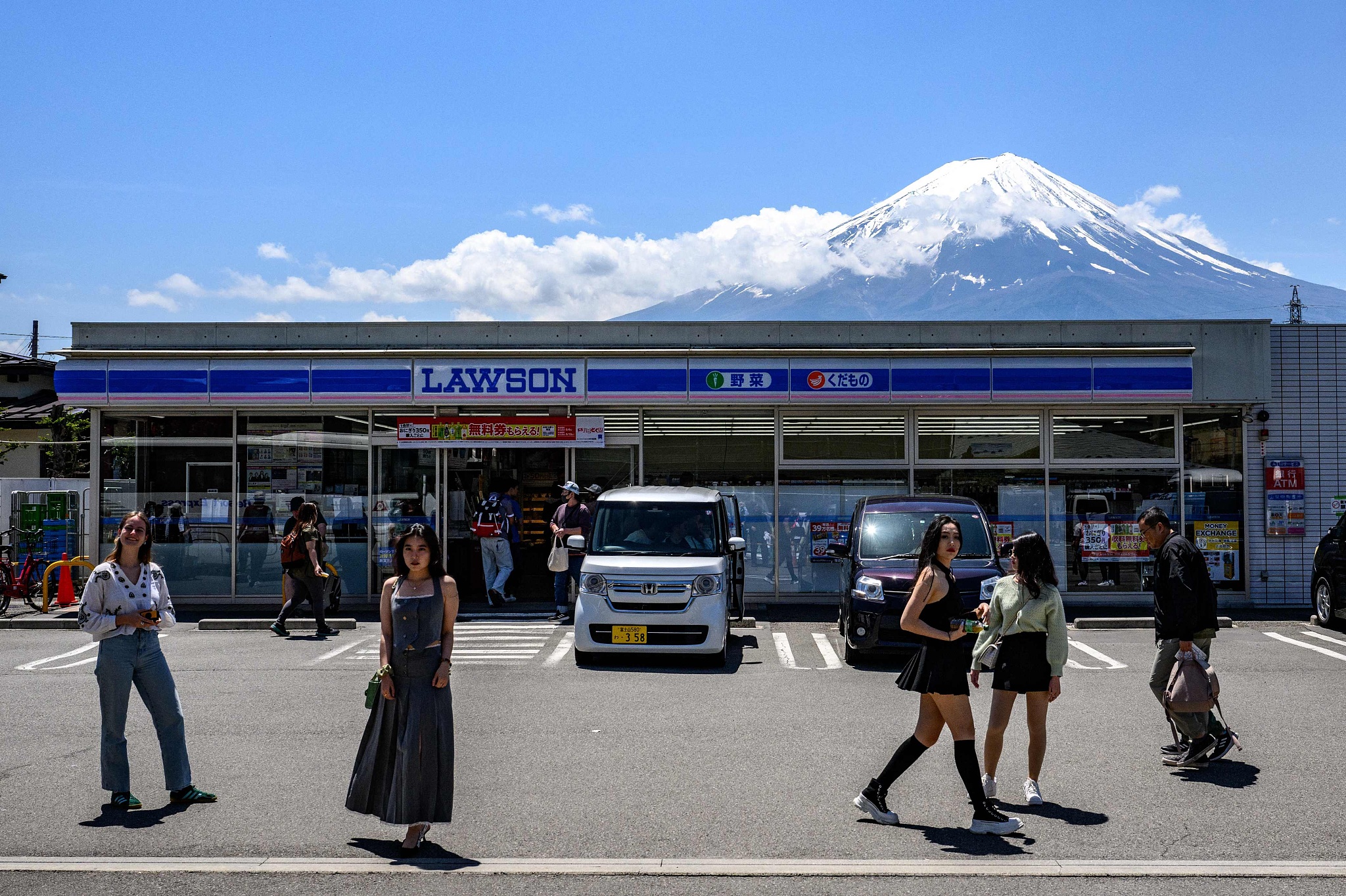 Tourists pose in front of a convenience store with Mount Fuji in the background, Yamanashi Prefecture, Japan, May 3, 2024. /CFP