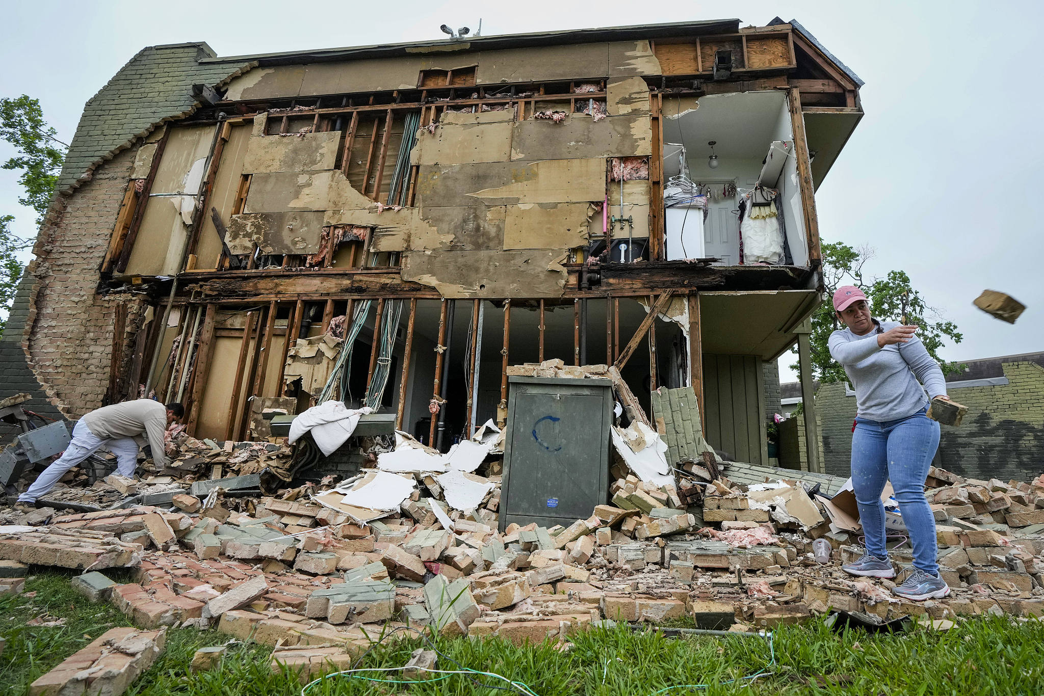 Residents clean up debris after a wall came down at an apartment complex in the aftermath of a severe storm, Houston, Texas, U.S., May 17, 2024. /CFP