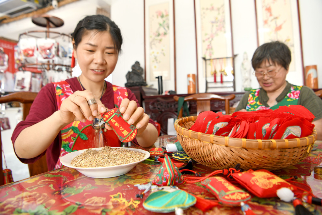 Two women fill embroidered sachets with herbs in Shouxian County of Huainan, Anhui Province on May 21, 2024. /CFP