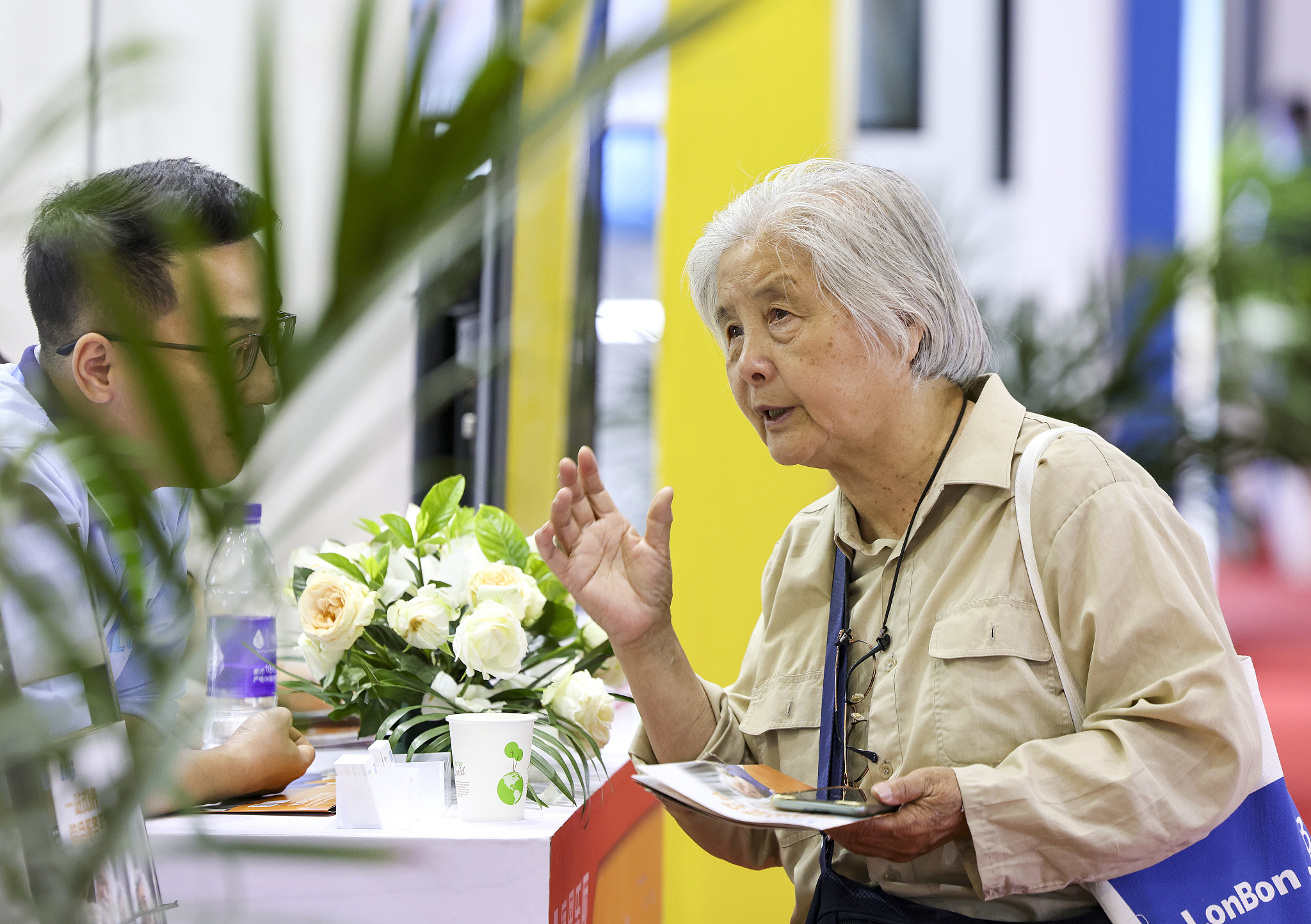 An attendee of the 10th China International Senior Services Expo engages with an exhibitor, Beijing, China, May 21, 2024. /CFP 