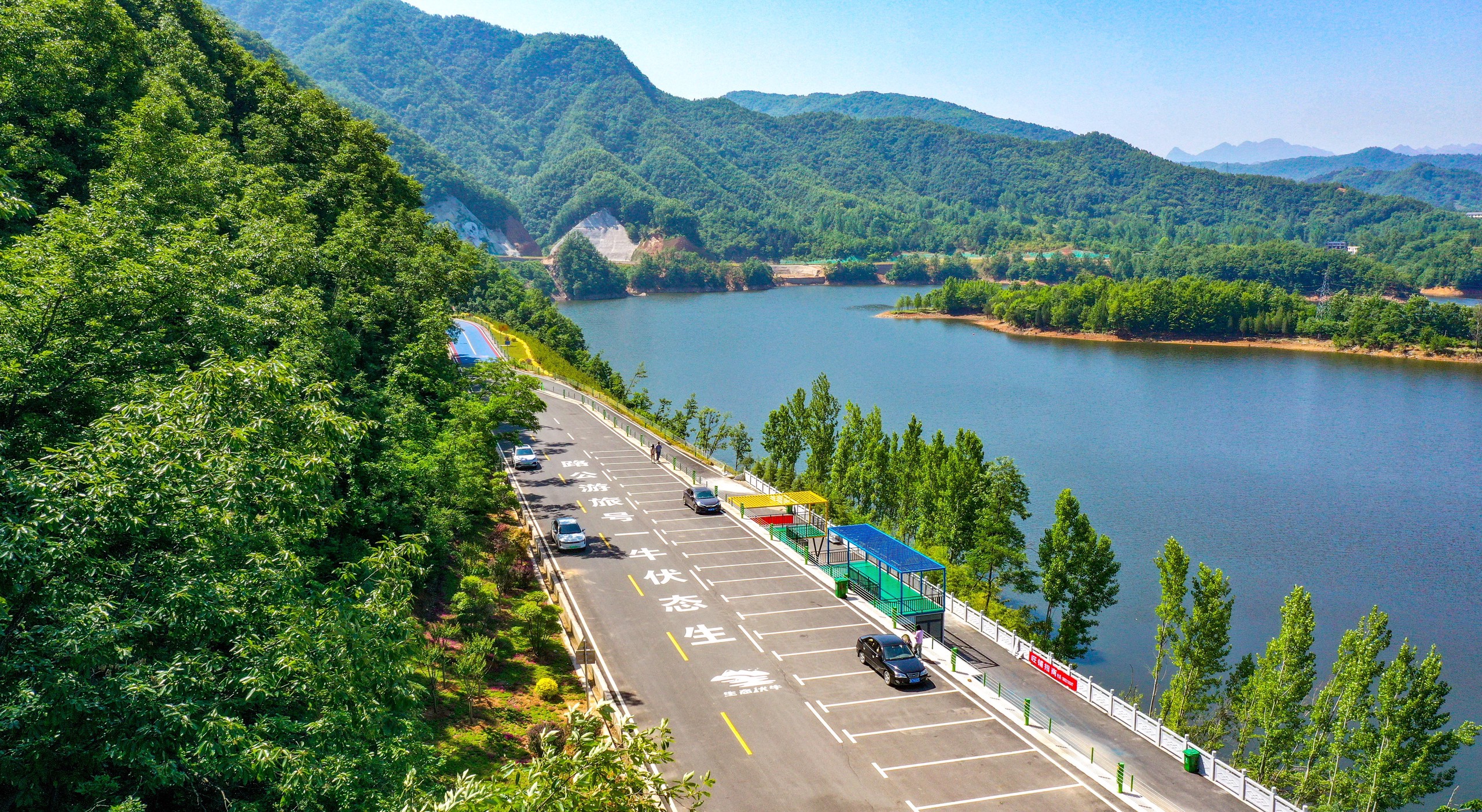 A photo taken on May 22, 2024 shows a lakeside view of the Eco-Funiu No.1 Tourism Highway in Luoyang, Henan Province set against the backdrop of the Funiu Mountain. /IC