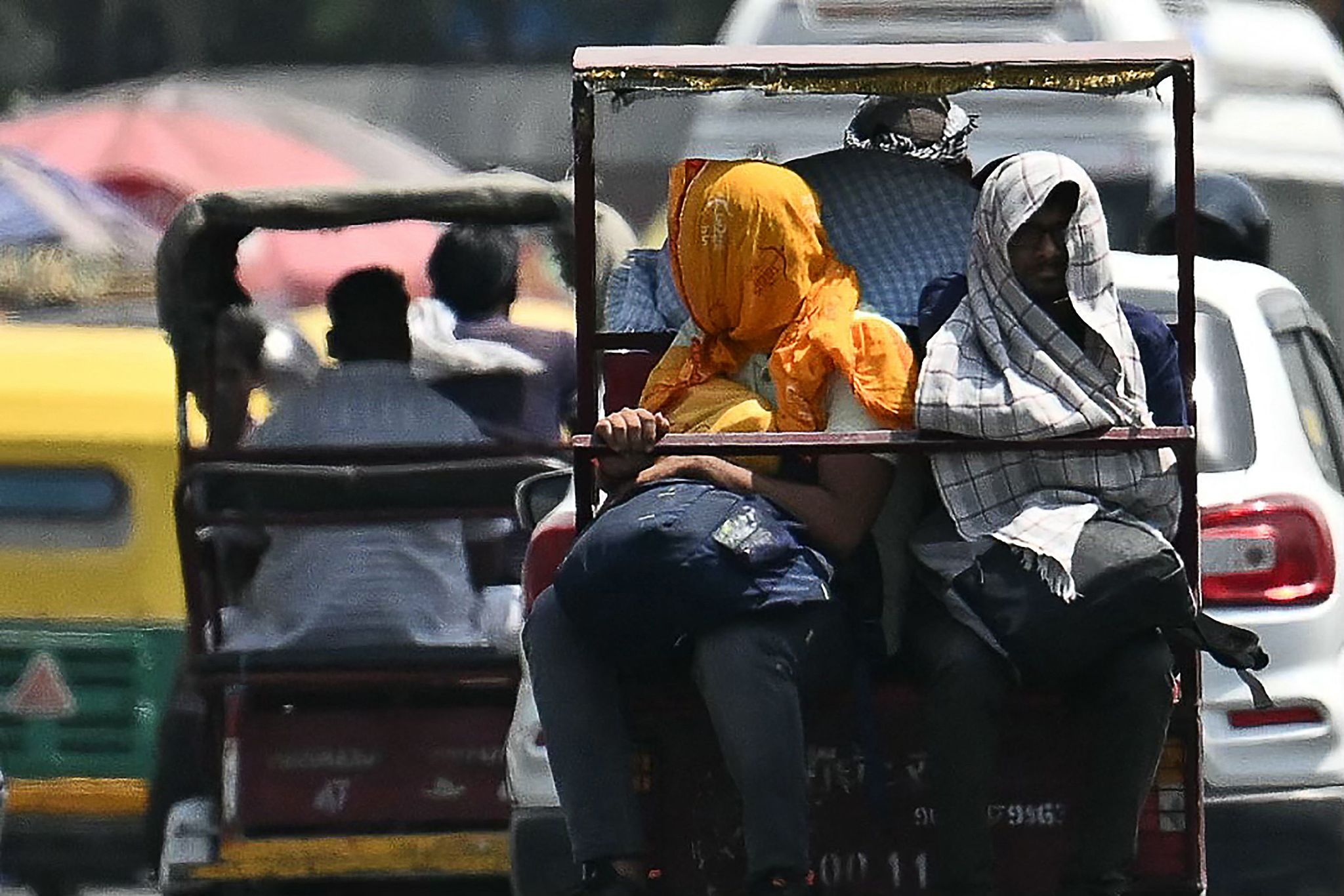 People traveling on an electric rickshaw cover their heads to shelter from the sun during a hot summer day in the old quarters of New Delhi. May 21, 2024. /CFP