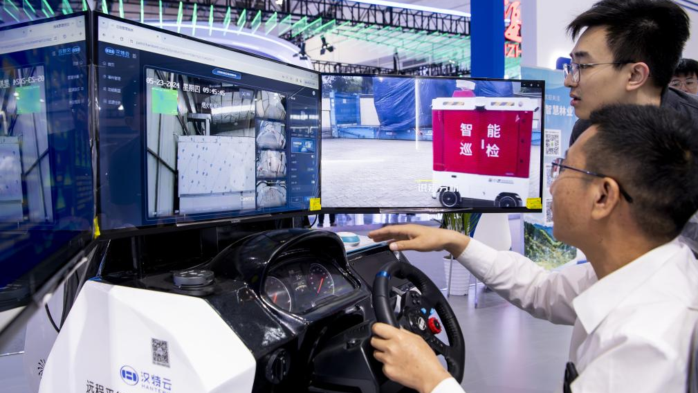 A visitor (R) tries remote parallel driving system at the on-site experience area for the 7th Digital China Summit in Fuzhou City, southeast China's Fujian Province, May 23, 2024. /Xinhua