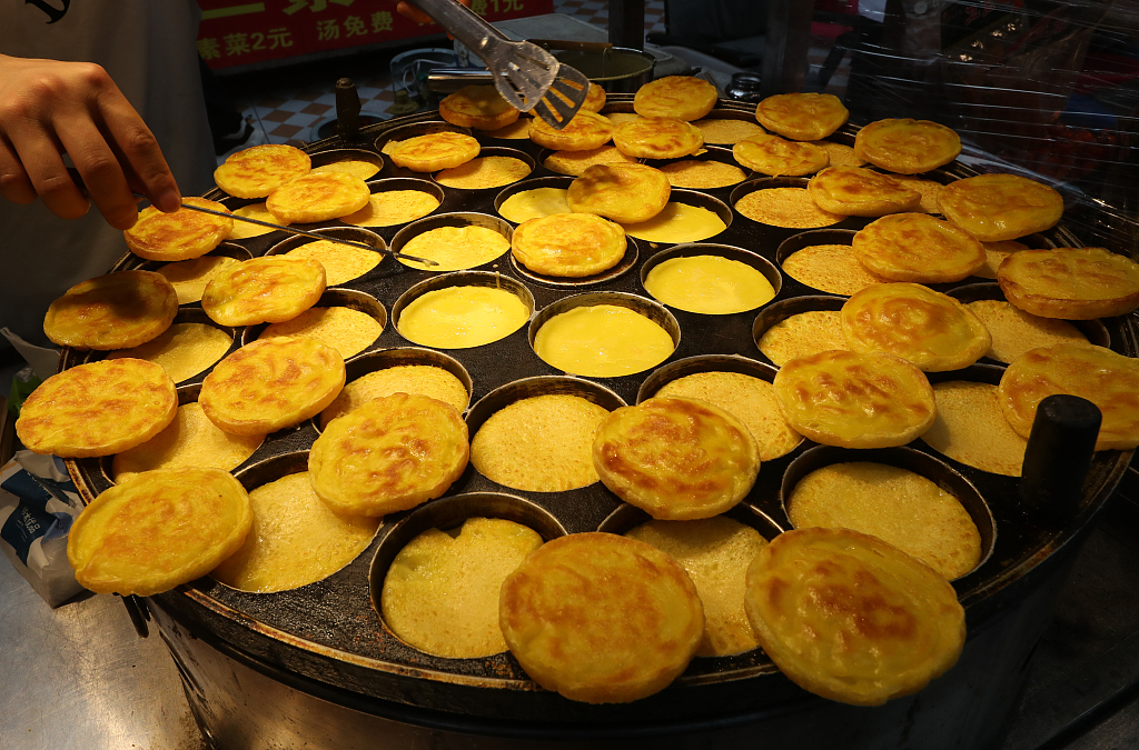Corn cakes are made at a stall in the Shuangqiao night market in Kunming, Yunnan Province on May 23, 2024. /CFP